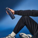 A dark gray water bottle stands upright with a flip-top lid and textured grip on a plain white background. Branding on the bottle reads ION8.