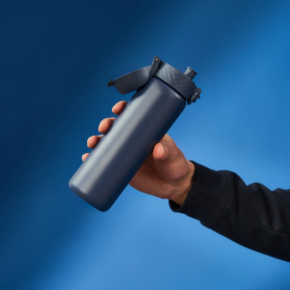 A dark gray water bottle stands upright with a flip-top lid and textured grip on a plain white background. Branding on the bottle reads ION8.