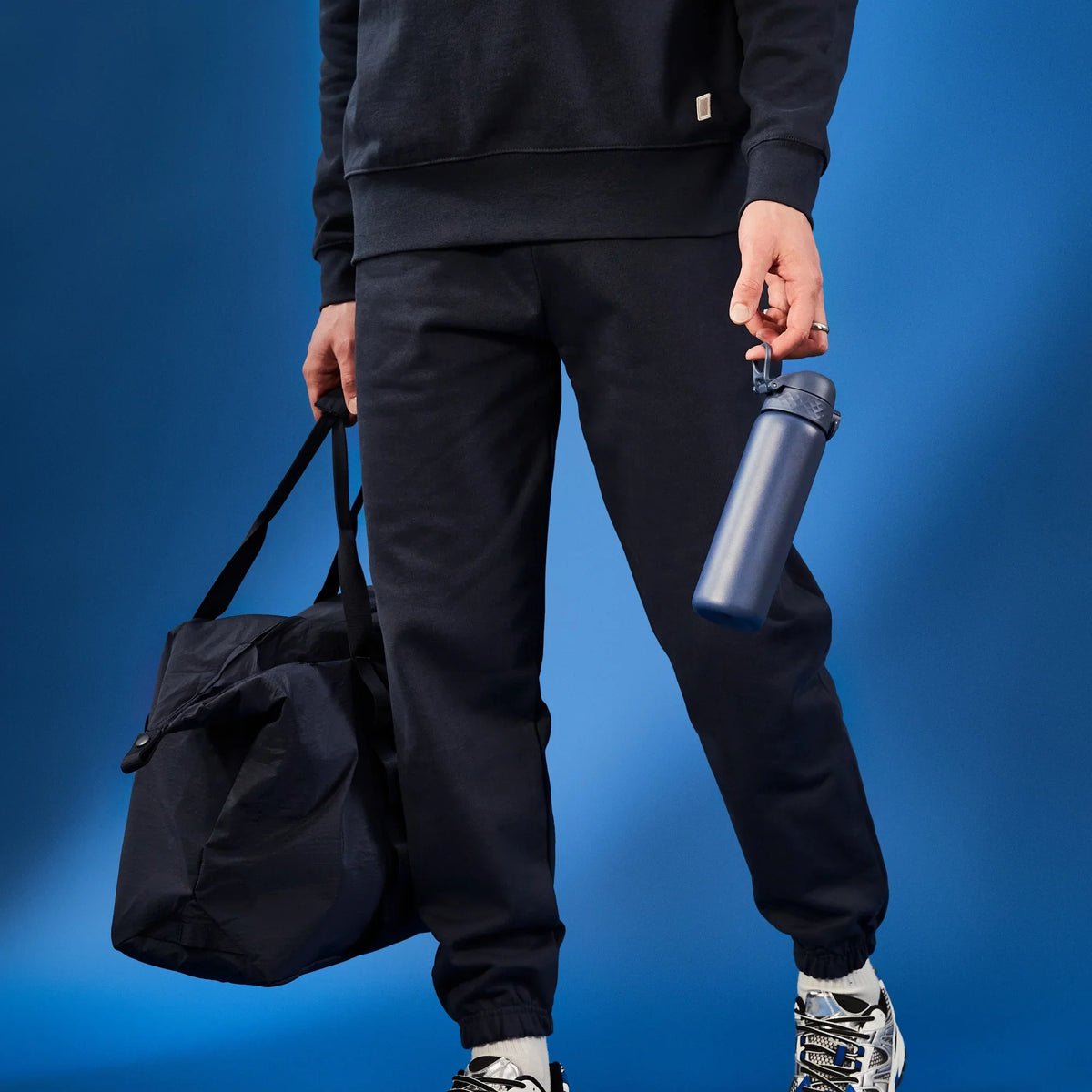 A dark gray water bottle stands upright with a flip-top lid and textured grip on a plain white background. Branding on the bottle reads ION8.