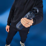 A dark gray water bottle stands upright with a flip-top lid and textured grip on a plain white background. Branding on the bottle reads ION8.