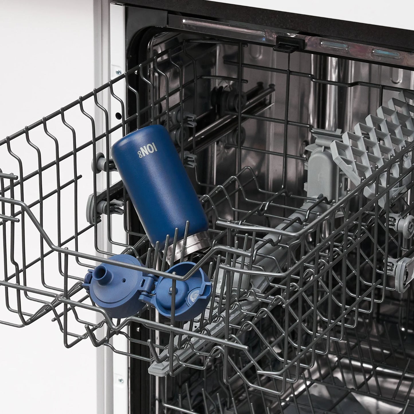 A blue water bottle labeled "ION8" is placed inside the top rack of an open dishwasher in a kitchen setting.