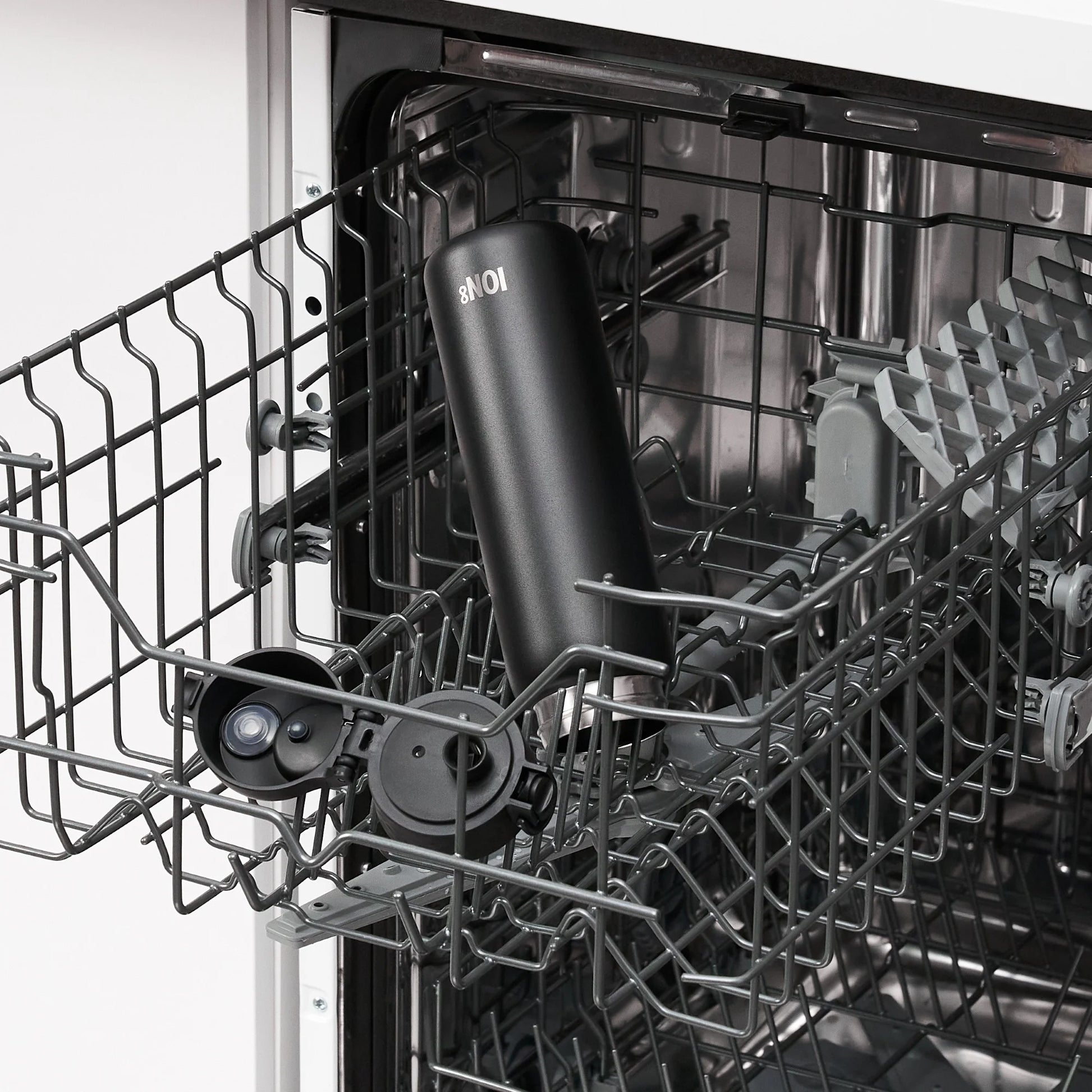 A black tumbler labeled "ION8" sits inside an open dishwasher rack amidst the metal interior and other compartments of the appliance.