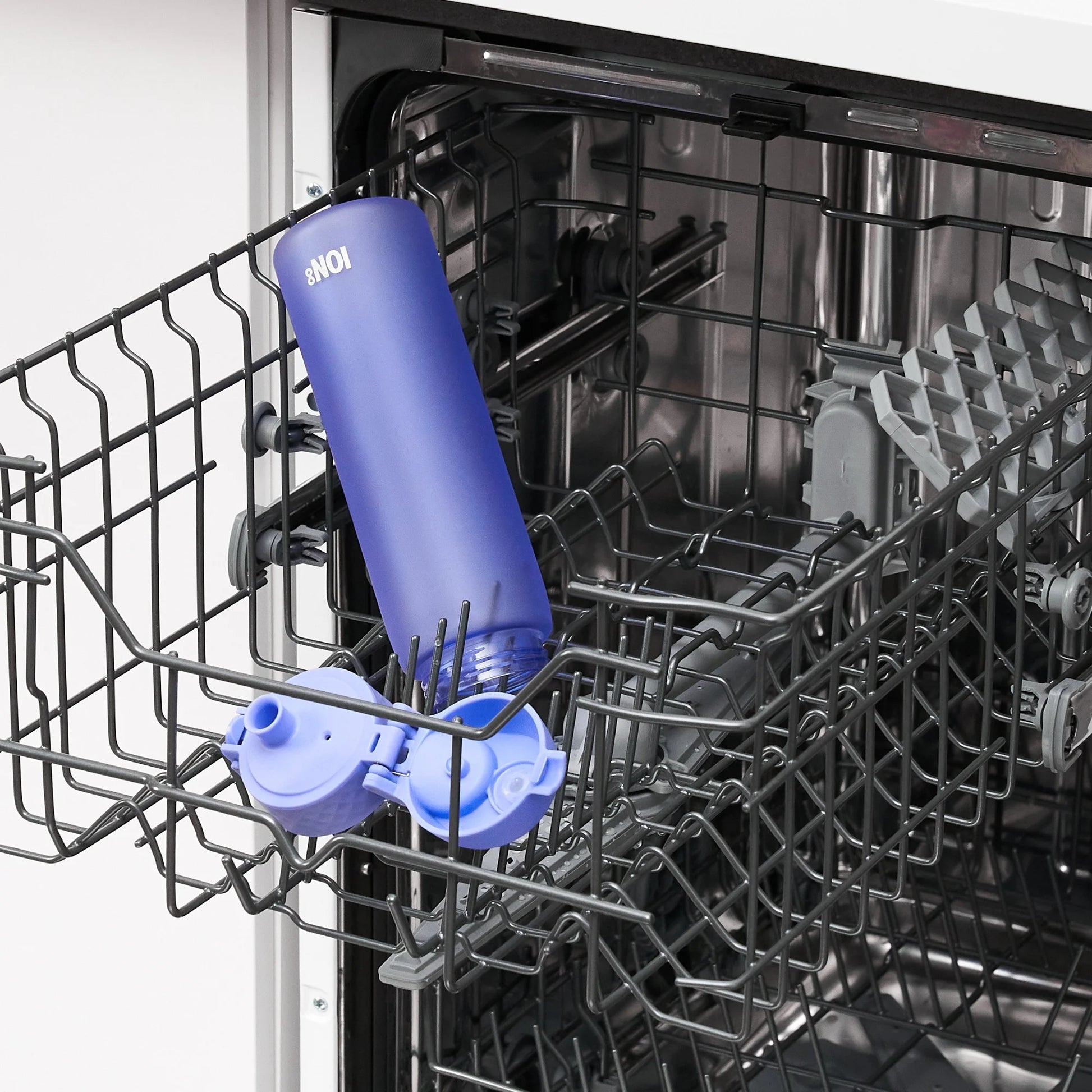 A blue water bottle labeled "8NOI" stands upside down inside a metal dishwasher rack in a kitchen setting.