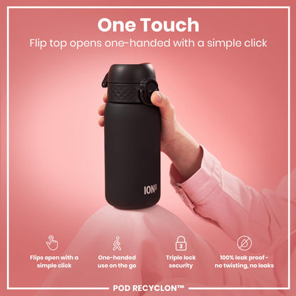 A black ION8 water bottle is held; its flip top opens one-handed. The bottle rests on pink fabric against a pink background; text highlights its features. "One Touch. Flip top opens one-handed with a simple click." "Flips open with a simple click. One-handed use on the go. Triple lock security. 100% leak proof - no twisting, no leaks. POD RECYCLON™"