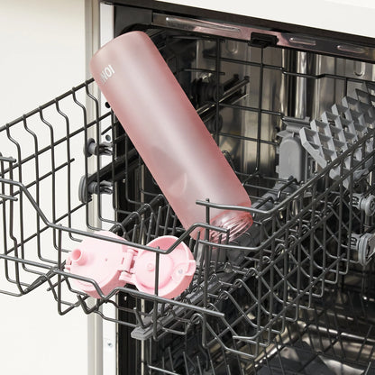 Pink water bottle labeled "ION8" lying on the top rack of an open dishwasher with a removable lid placed nearby in a kitchen setting.