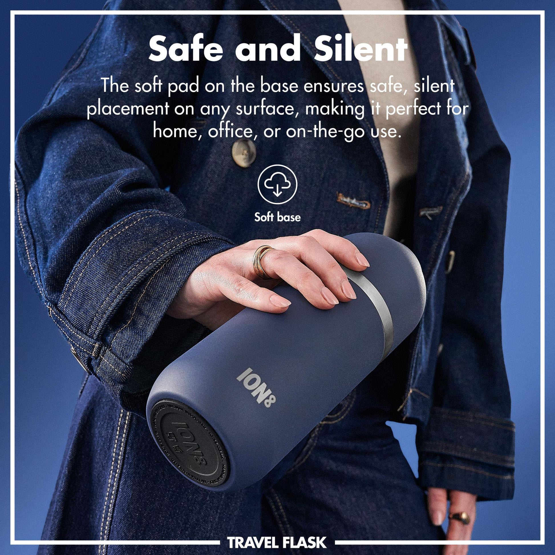 A person holds a blue travel flask with a soft base while wearing a denim jacket against a blue background. Text: Safe and Silent The soft pad on the base ensures safe silent placement on any surface making it perfect for home office or on-the-go use. Soft base TRAVEL FLASK ION8.