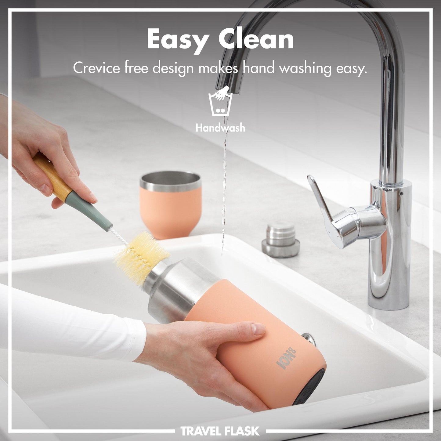 A person cleans a peach-colored travel flask with a brush under a running tap in a sink Easy Clean Crevice free design makes hand washing easy Handwash ION8 TRAVEL FLASK