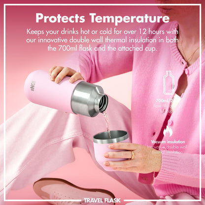 A person pours liquid from a pink insulated travel flask into a matching cup while sitting against a pink background. Text reads: "Protects Temperature" "Keeps your drinks hot or cold for over 12 hours with our innovative double wall thermal insulation in both the 700ml flask and the attached cup" "700ml/24oz flask fills over 2 full cups" "Vacuum insulation Innovative double wall thermal insulation" "TRAVEL FLASK".